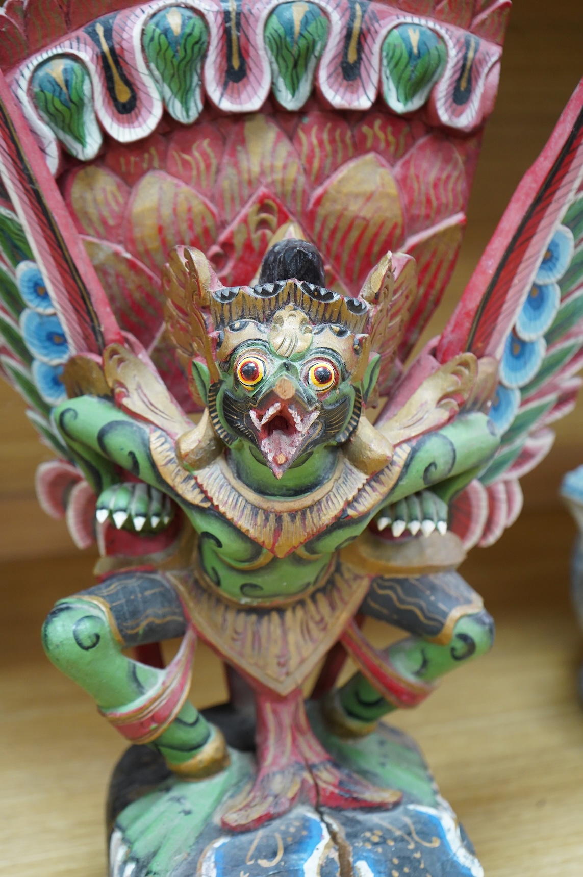A Balinese painted and carved wood sculpture of Garuda, together with a smaller similar carving, largest 46cm high